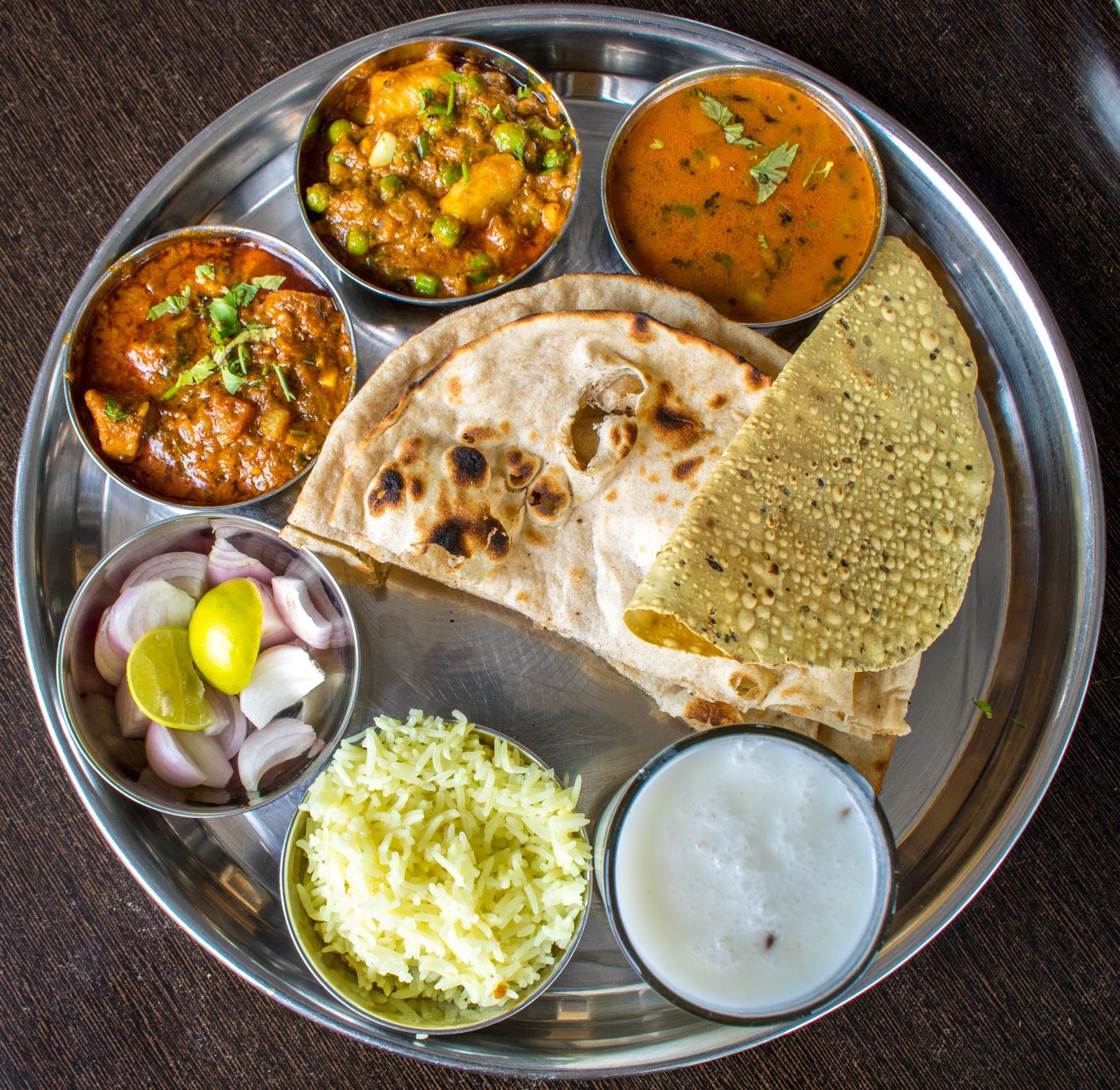 A steel thali with dal, curries, naan and rice